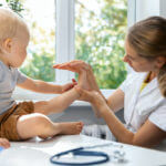 female orthopedist examining little child foot condition in clinic