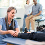 Physical therapist works on man's sprianed foot during physical therapy